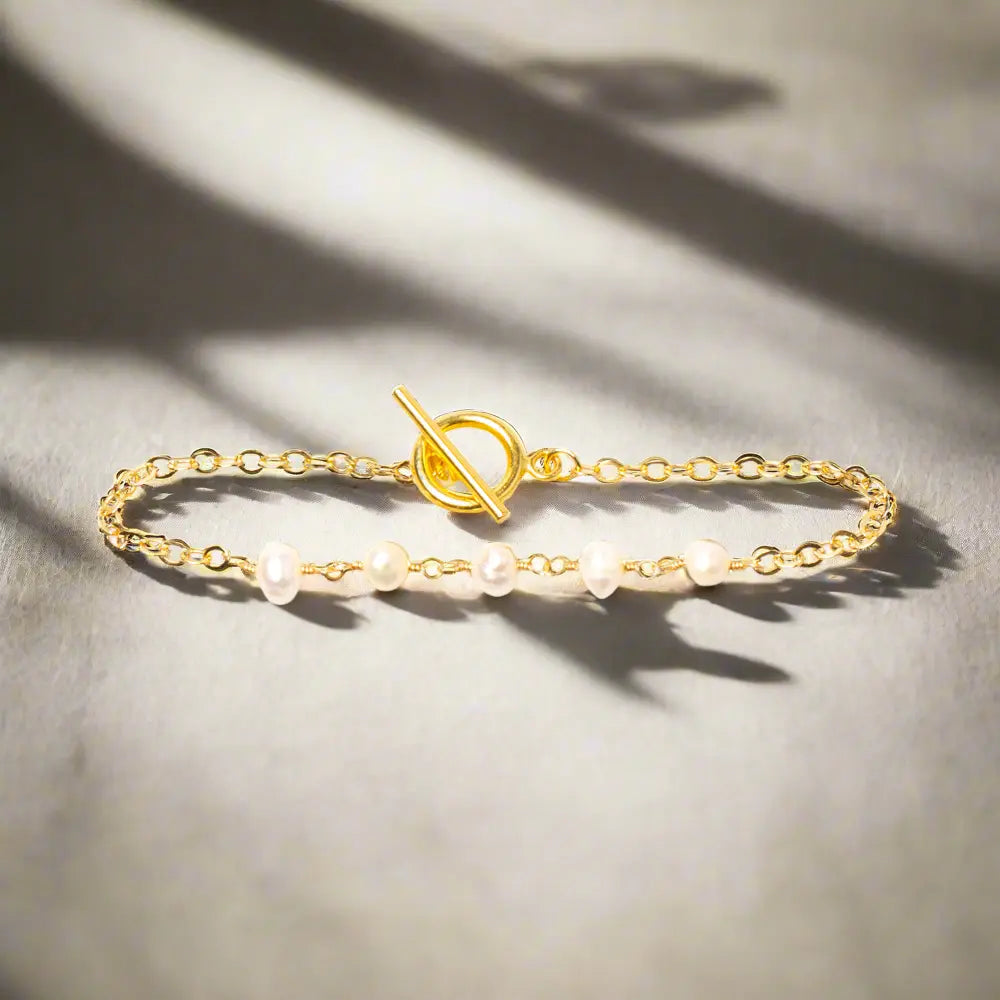 Delicate gold-plated pearl bracelet with chain design, stylish jewelry by Suzie Blue Canada, featuring small pearls and intricate chain links.
