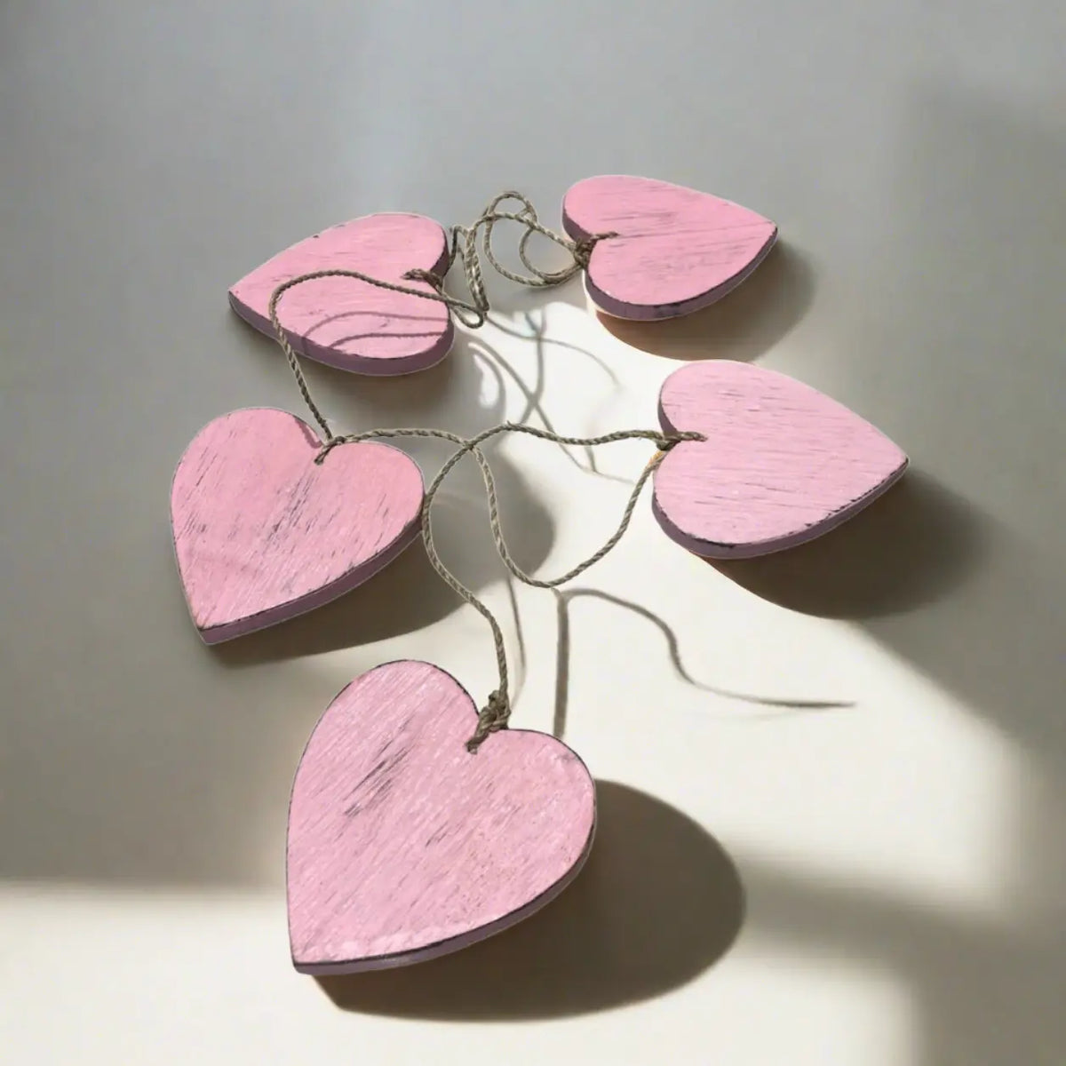 Set of five hanging wooden heart string decor by Suzie Blue Canada, featuring rustic wooden hearts for home decoration.
