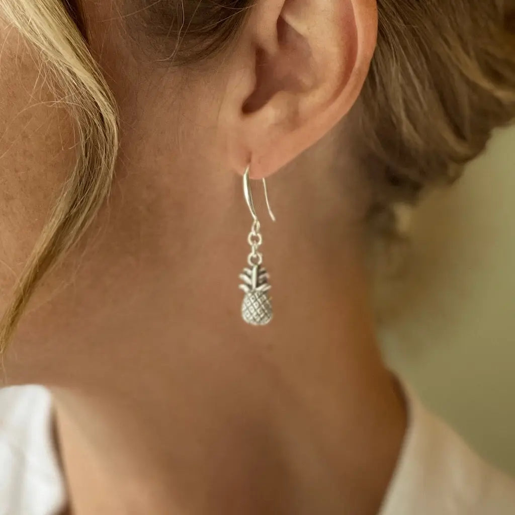 Silver plated pineapple charm earrings by Suzie Blue Canada featuring detailed pineapple designs and dangling earring style.