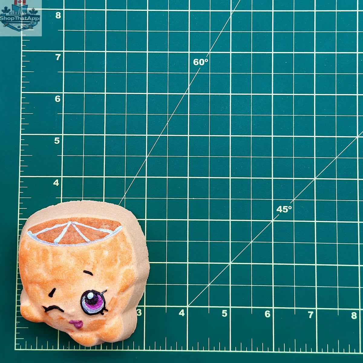 Bath and body orange with face from The Bomb Bar Canada, showcasing a vibrant orange-shaped bath bomb with facial features.