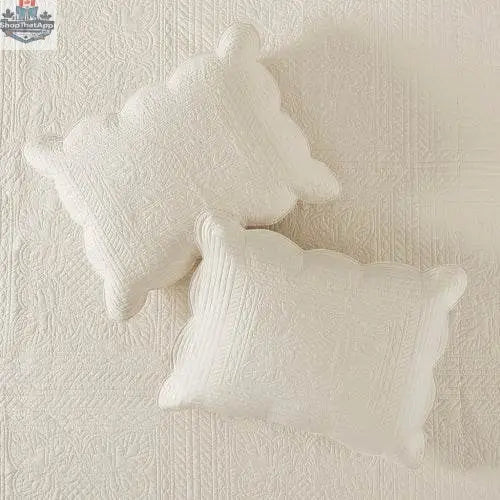 Reversible scalloped edge quilt set comforter from EX-STOCK Canada with coordinating pillow shams on a bed.