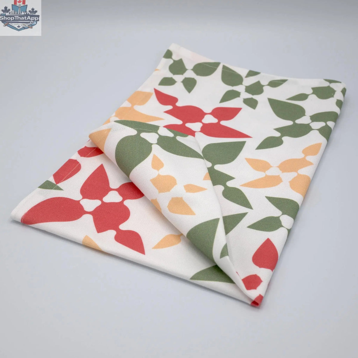 Pink printed cotton kitchen tea towel from Hem and Tassel's Celebration collection, neatly folded and showcasing festive design.