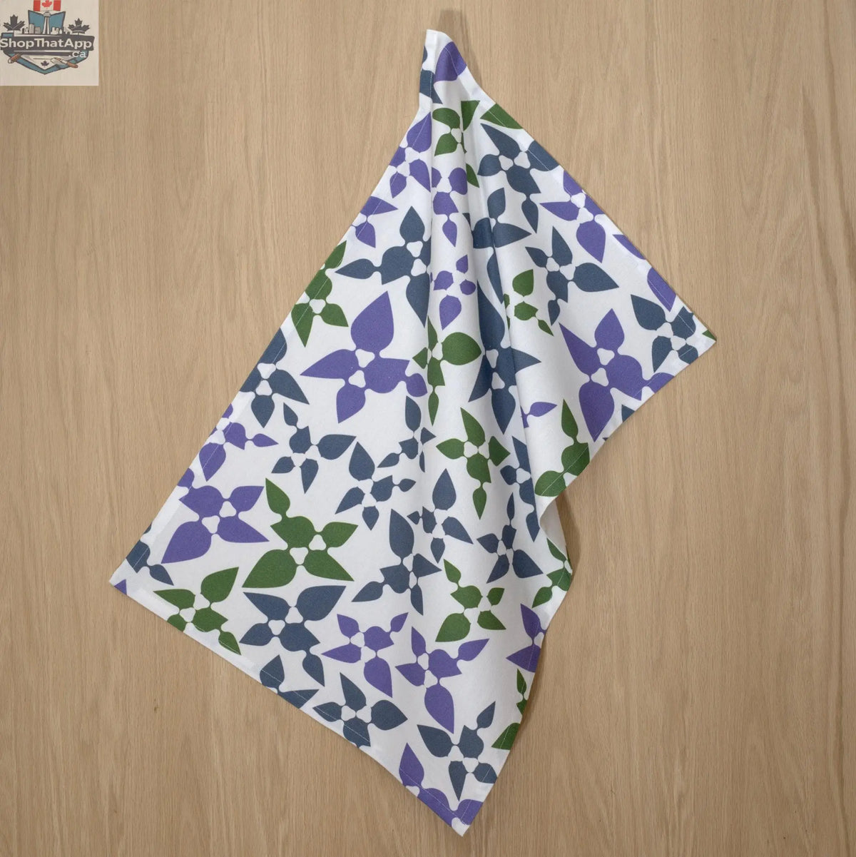 Purple printed cotton kitchen tea towel with celebration design, hanging from a hook, by Hem And Tassel.