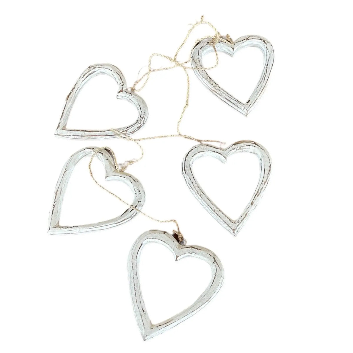 String of open wooden heart decorations hanging on a wall, perfect for home decor by Suzie Blue Canada.
