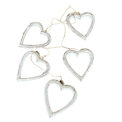 String of open wooden heart decorations hanging on a wall, perfect for home decor by Suzie Blue Canada.