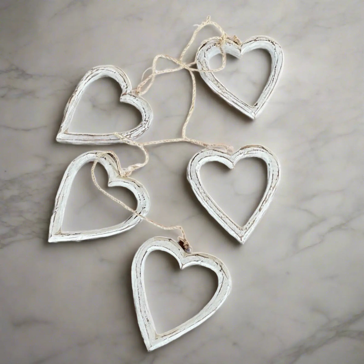 String of open wooden heart decorations hanging on a wall, perfect for home decor by Suzie Blue Canada.
