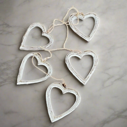 String of open wooden heart decorations hanging on a wall, perfect for home decor by Suzie Blue Canada.
