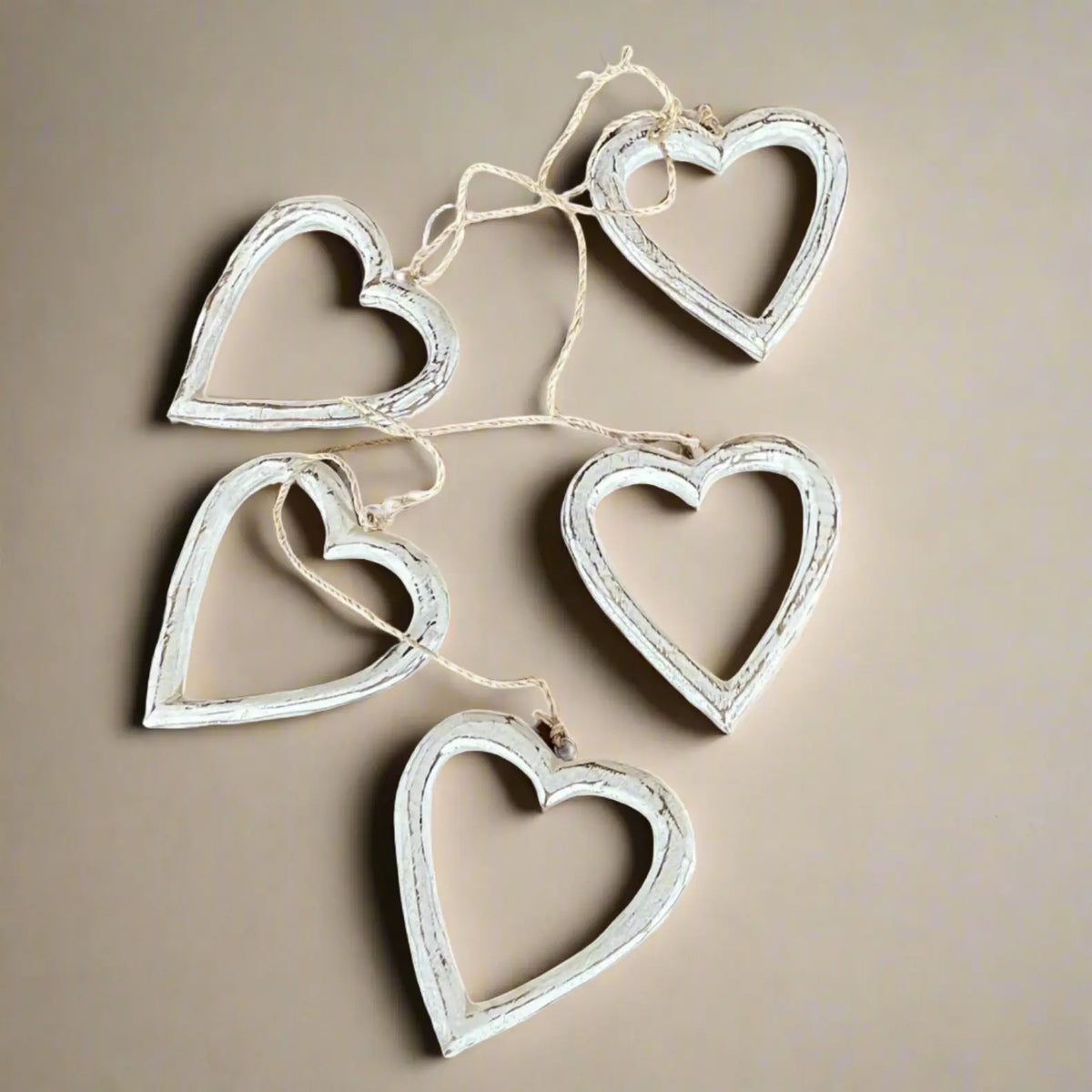 String of open wooden heart decorations hanging on a wall, ideal for home decor, by Suzie Blue Canada.