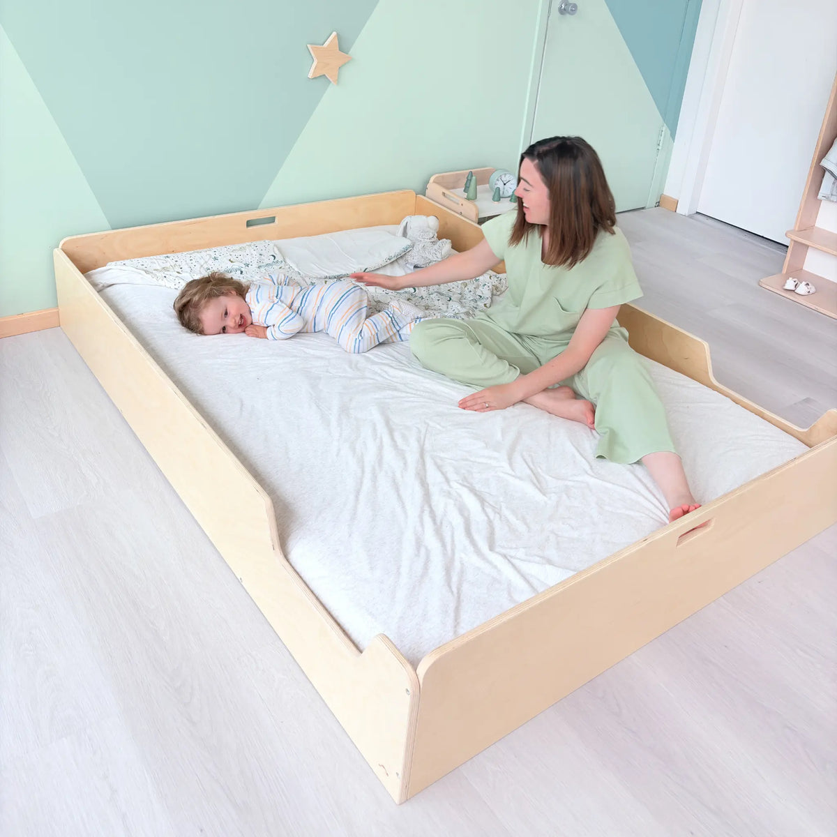 Apple Full Montessori floor bed for toddlers with safety rails, made by Sapiens Child, shown with soft bedding and natural wood finish.