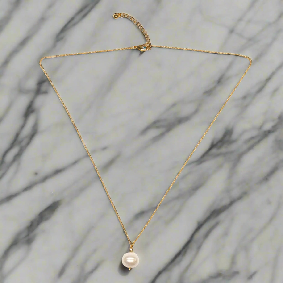 Gold-plated single pearl drop necklace from Suzie Blue Canada featuring a delicate pearl pendant on a fine chain.