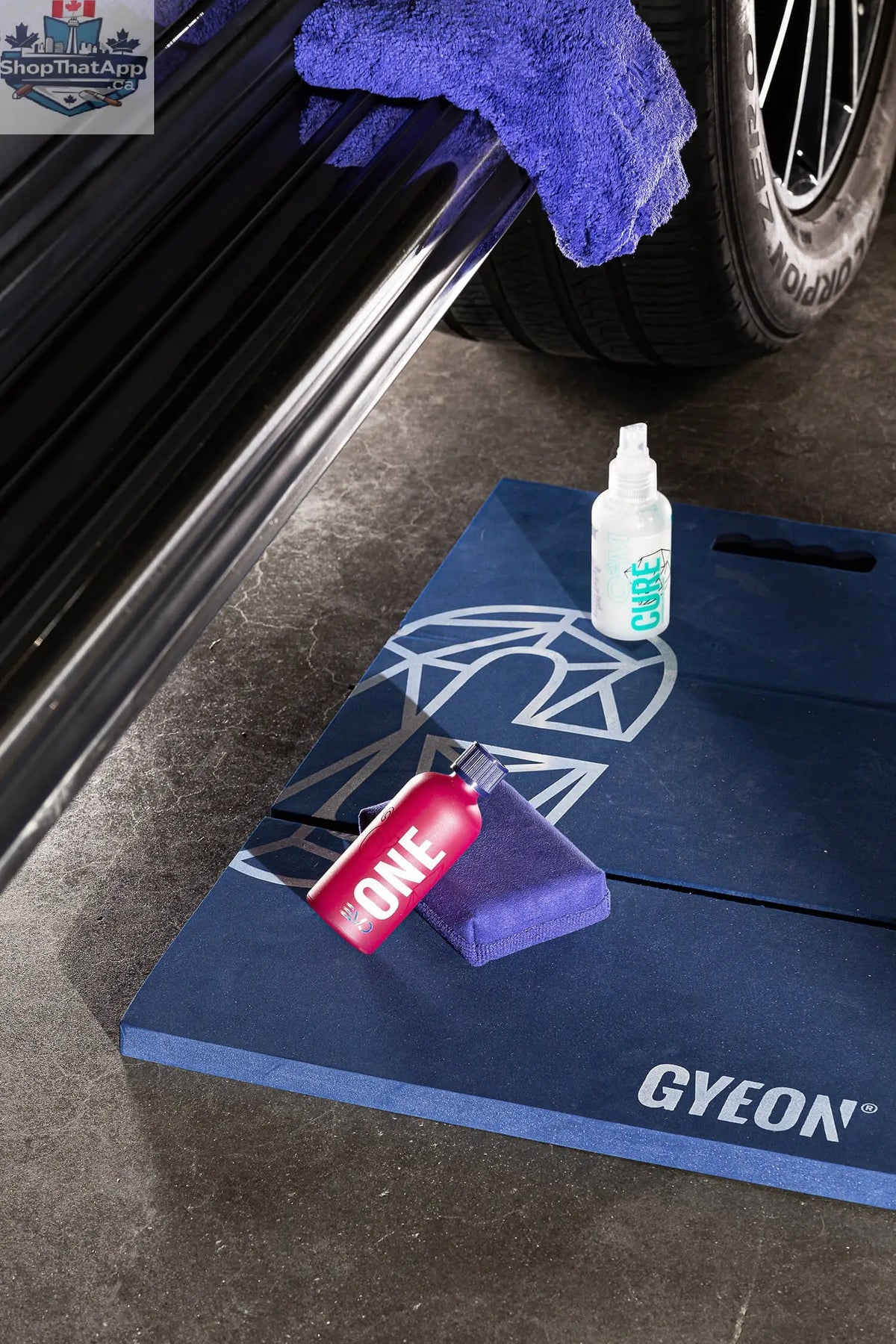 GYEON Q² One EVO ceramic coating kit with lightbox display, featuring bottles, applicator pads, and instruction manual on a clean surface.