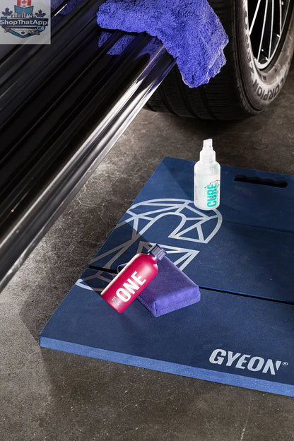 GYEON Q² One EVO ceramic coating kit with lightbox display, featuring bottles, applicator pads, and instruction manual on a clean surface.