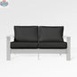 Enclover Hickory loveseat with white Sunbrella cushions, featuring a sturdy frame and comfortable seating for outdoor spaces.