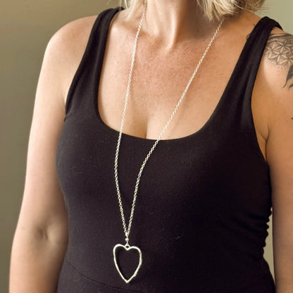 Silver chain necklace featuring a silver heart pendant with an open heart design from Suzie Blue Canada.