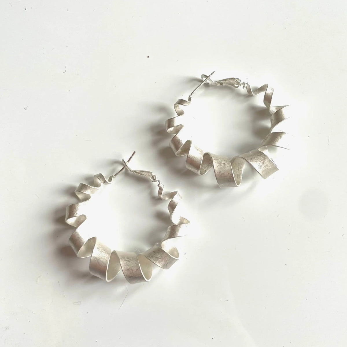 Silver plated spiral hoop stud earrings from Suzie Blue Canada, featuring small, sleek circular design perfect for everyday wear.