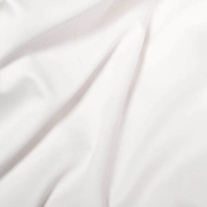 White Skylark+Owl Canada refined sateen fitted sheet on a bed with smooth, luxurious fabric and neatly fitted corners.