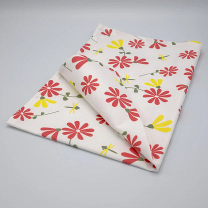 Pink and yellow printed Shy Dragonfly tea towel from Hem And Tassel, folded to showcase the colorful dragonfly design.