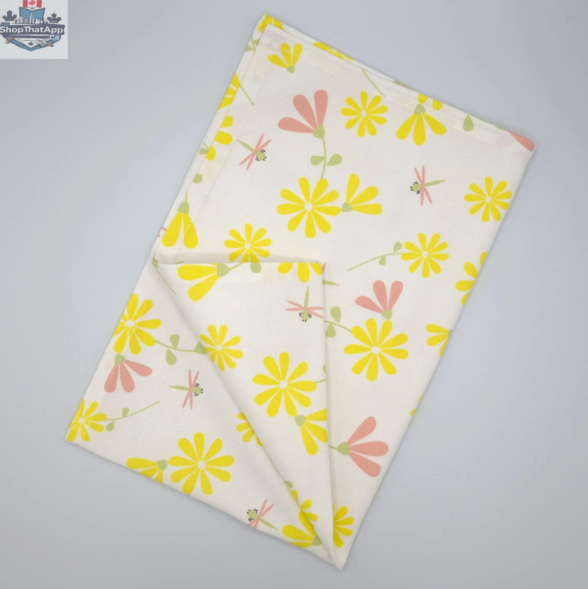 Printed Shy Dragonfly tea towel by Hem and Tassel, unfolded with yellow and blush floral design, showcasing vibrant kitchen decor.
