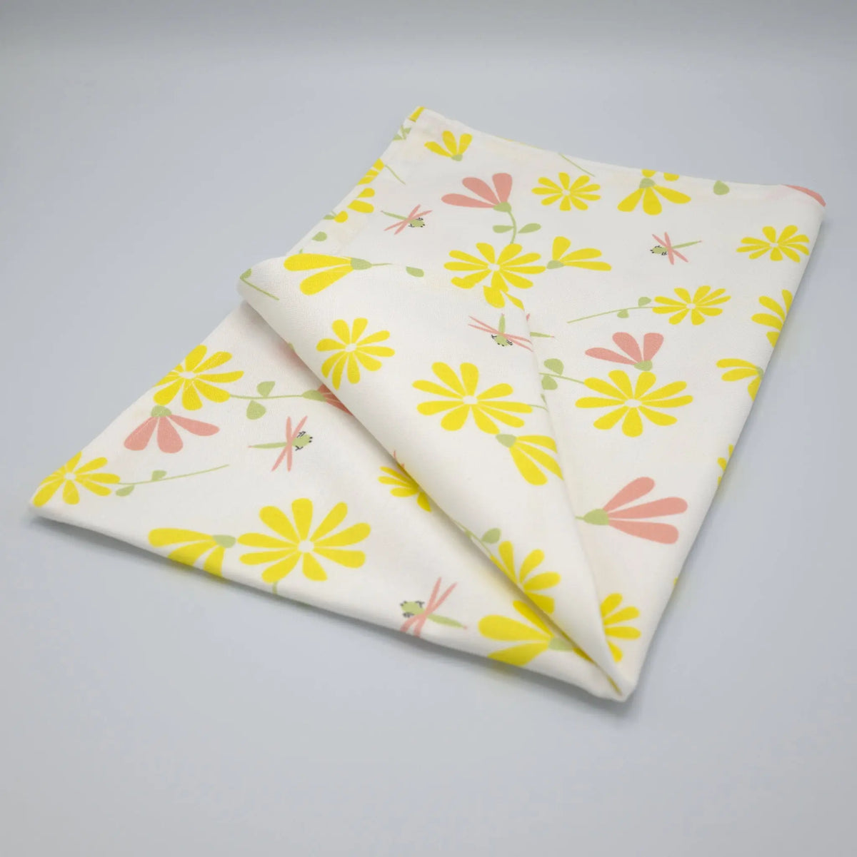 Hem and Tassel printed yellow and blush dragonfly tea towel folded, showcasing a vibrant, decorative kitchen towel design.