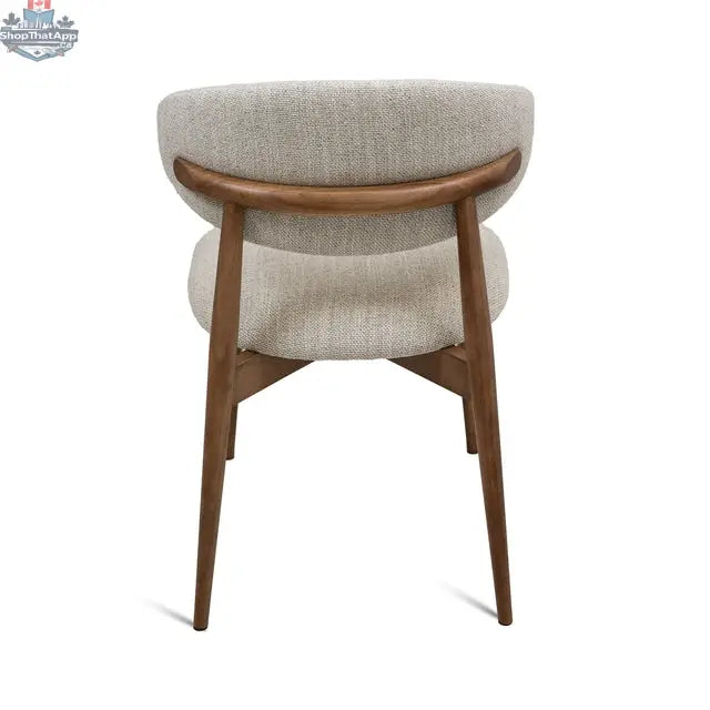 Cammy dining chair with beige fabric upholstery and walnut wood legs, shown from the back angle. Hygge Design House.