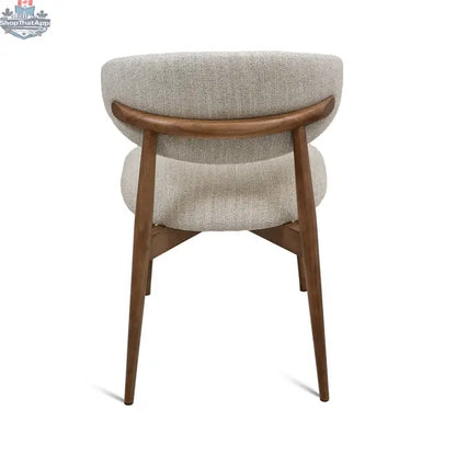 Cammy dining chair with beige fabric upholstery and walnut wood legs, shown from the back angle. Hygge Design House.
