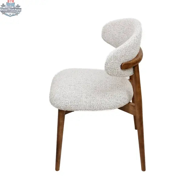 Beige Cammy Dining Chair by Hygge Design House with curved back, fabric upholstery, and walnut wood frame, side view.
