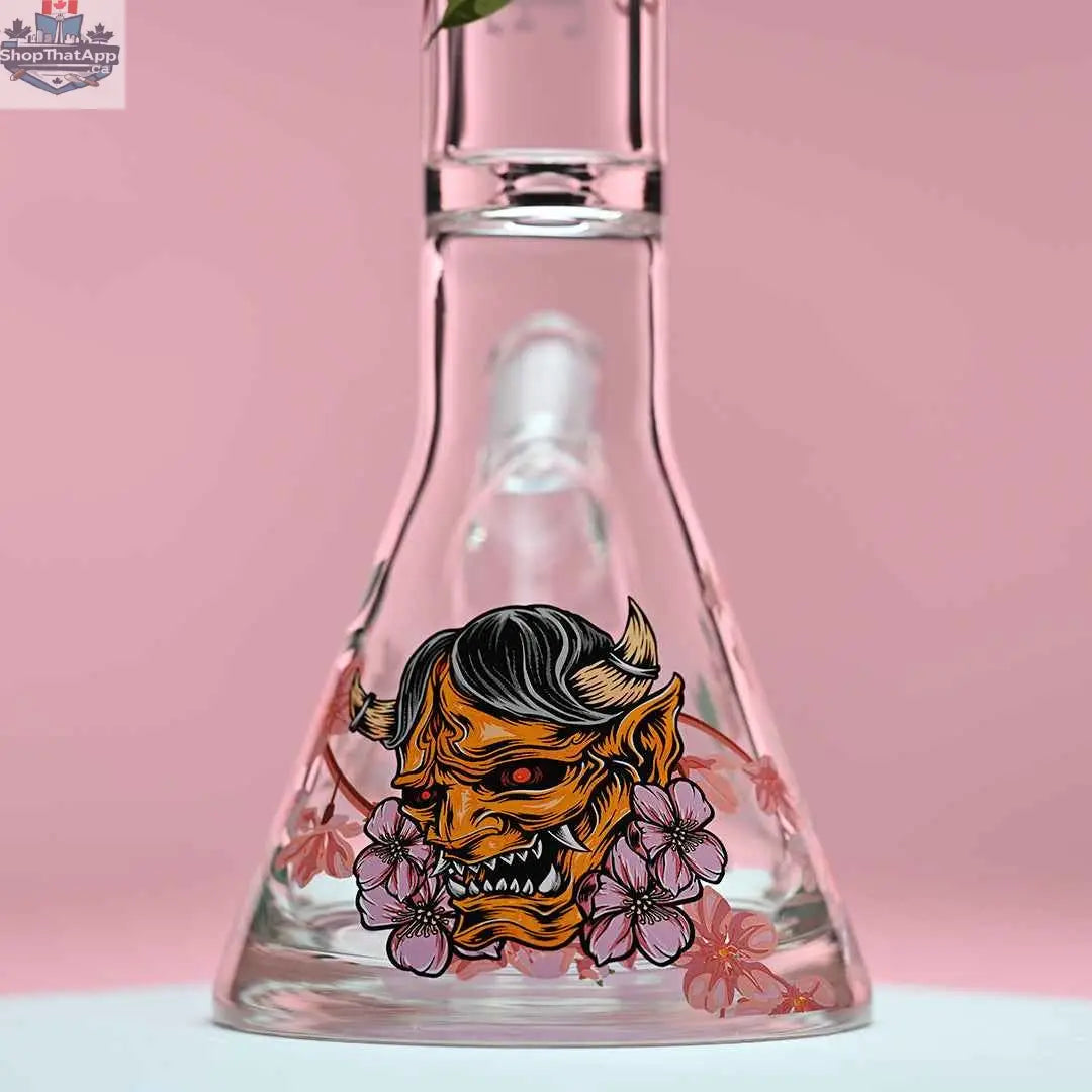 Close-up of Castle Glassworks 16-inch cherry blossom beaker bong with pink background, showing its 9mm thick glass base.