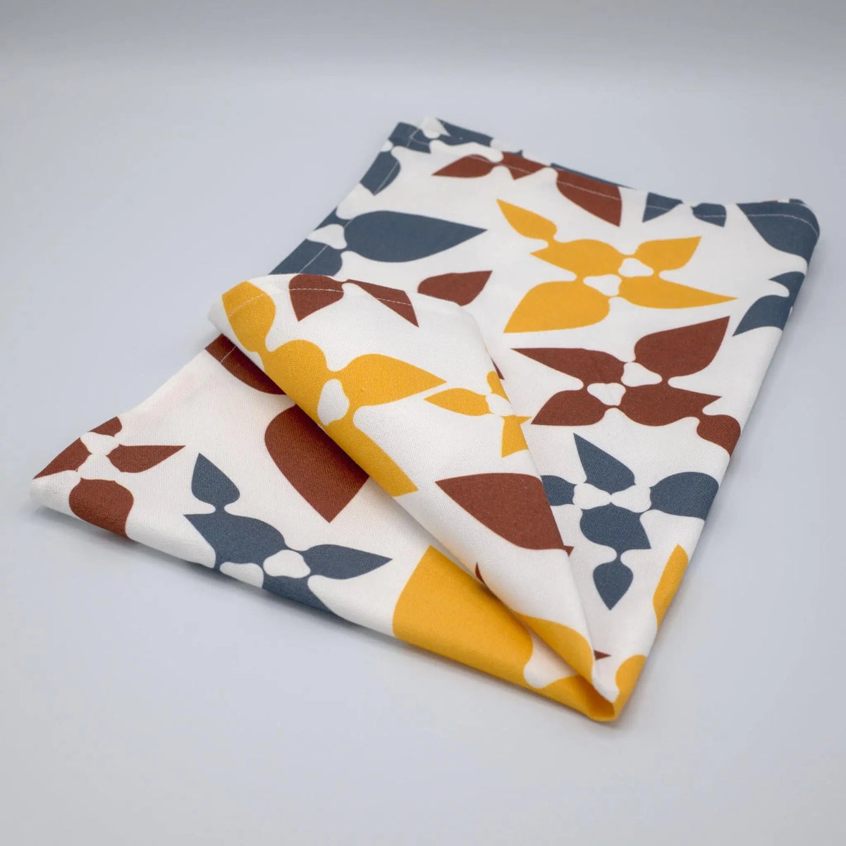 Folded Celebration Cotton Tea Towel by Hem And Tassel featuring printed design on soft cloth kitchen towel.