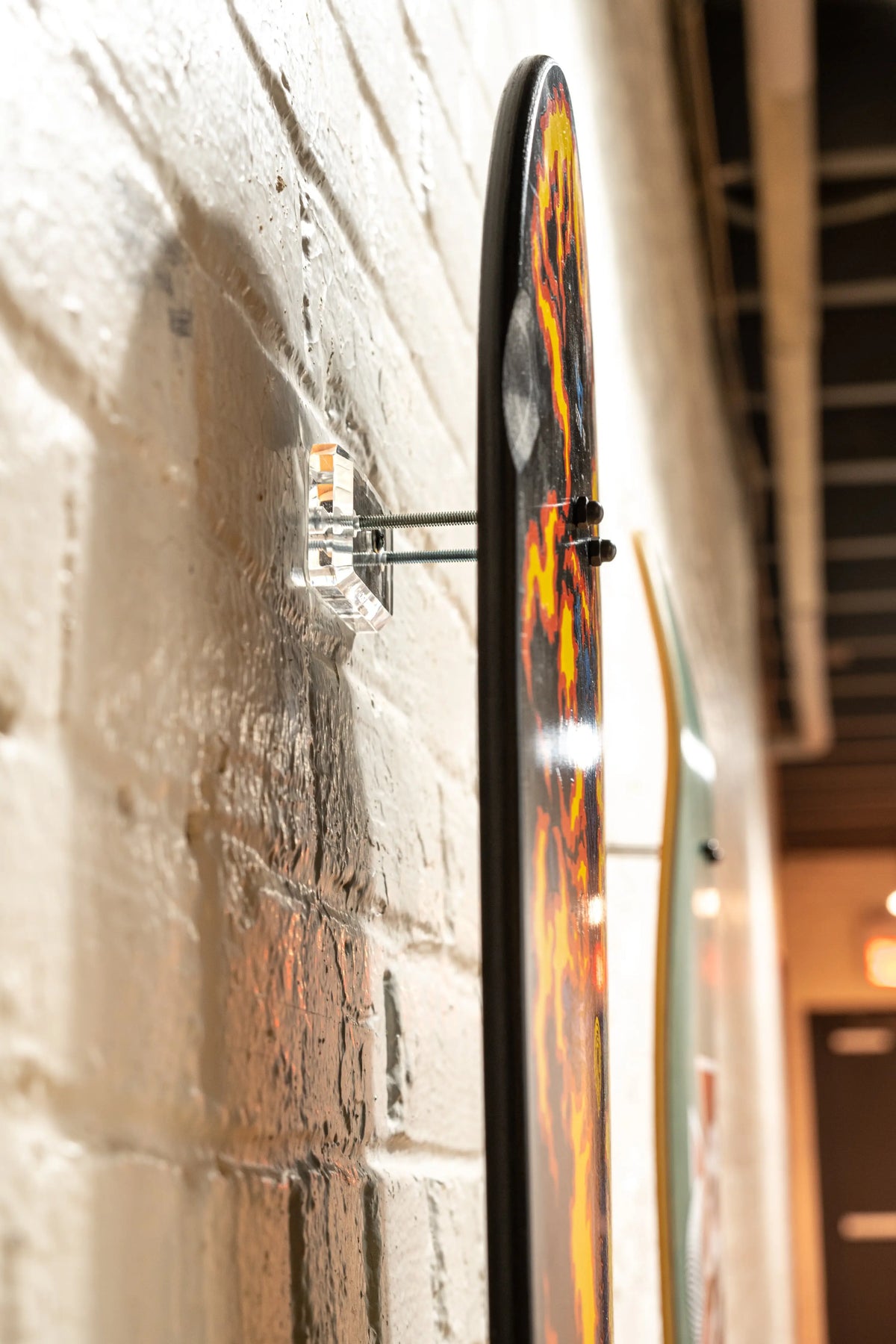 Clear skateboard wall mount hanger by Ghost Mounts displaying a deck with Supreme, Tommy Guerrero, and Powell Peralta graphics.