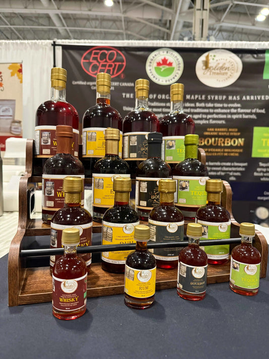 Golden Treasure Maple Syrup bottle collection showing four sizes of oak barrel aged maple syrup in clear glass bottles.
