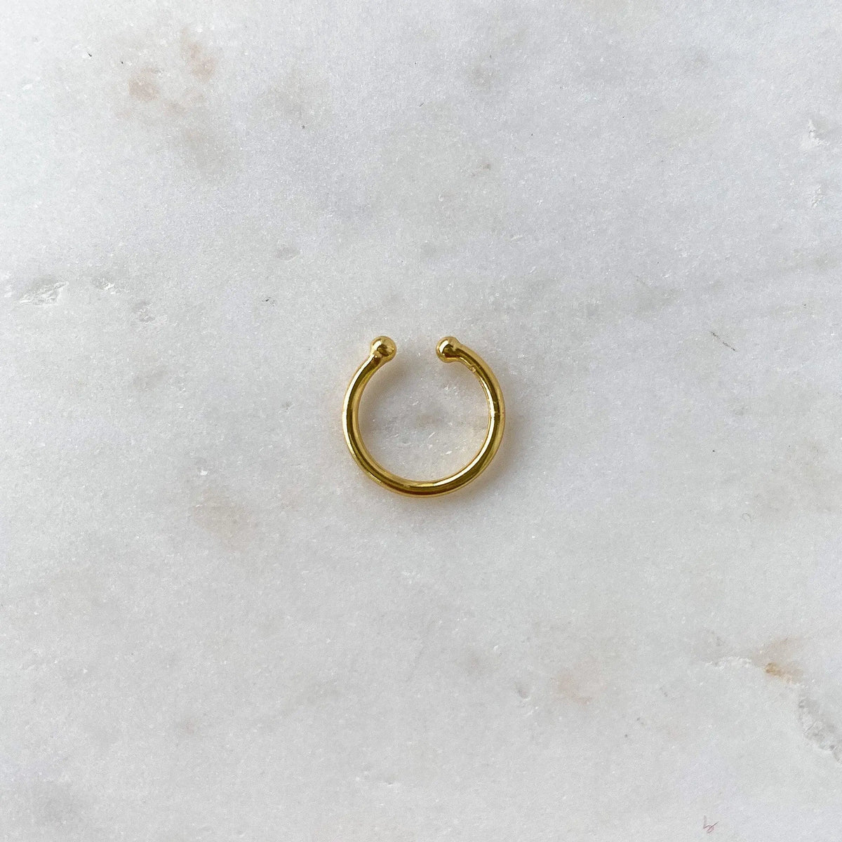 Gold ear cuff from HoraceJewelry featuring a simple, elegant design in a basic style, shown on a model's ear.