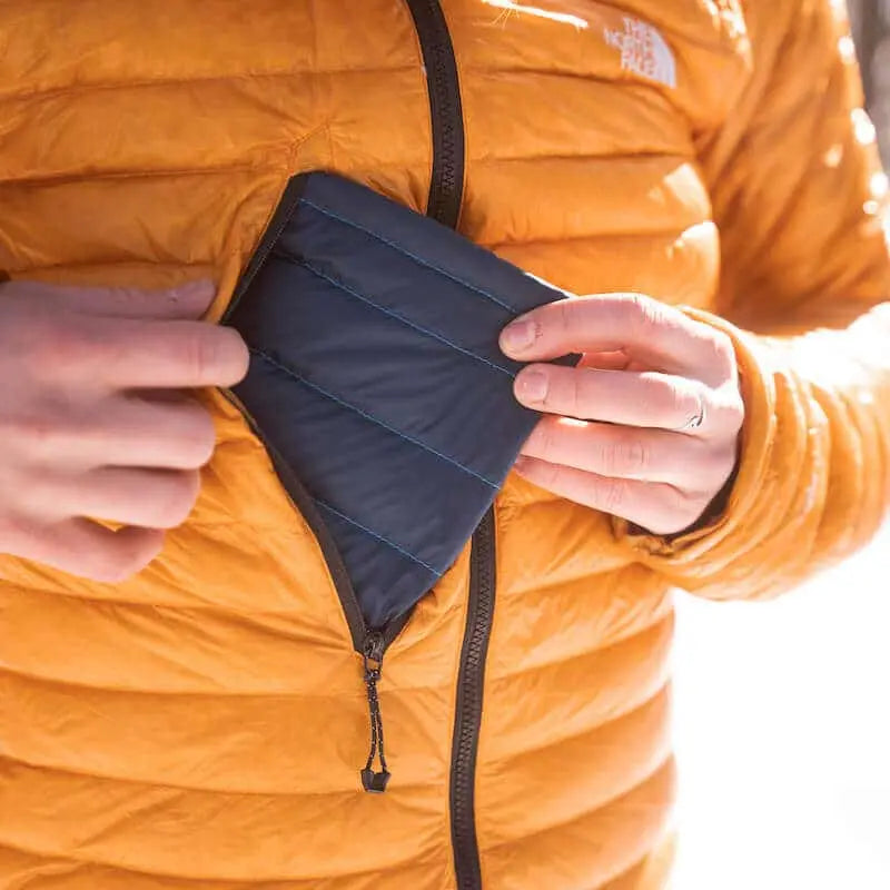 Hot Poc Sleeper eco reusable heat pack inside a coat, designed for outdoor phone protection and warmth.