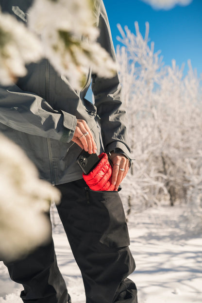 Hot Poc Eco Reusable Heat Pack designed for outdoor phone protection, shown protecting a smartphone outdoors in the image.