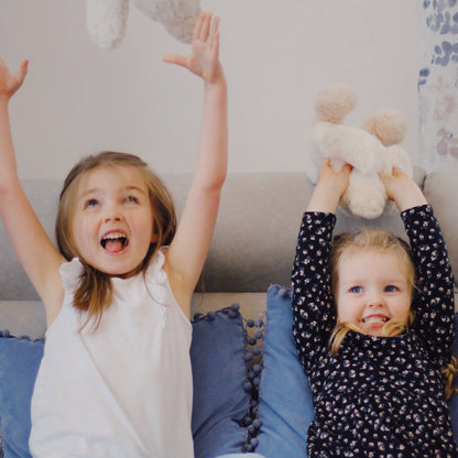 Young girls holding Hot Poc Thermy Buddy™ cozy heated plush toy in the shape of a giant squashed duck.