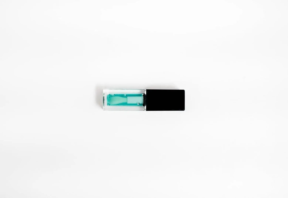 FencyGrace vegan fruit repulpant lip oil in a clear glass bottle with a gold cap, showcasing vibrant fruit ingredients for lip care.