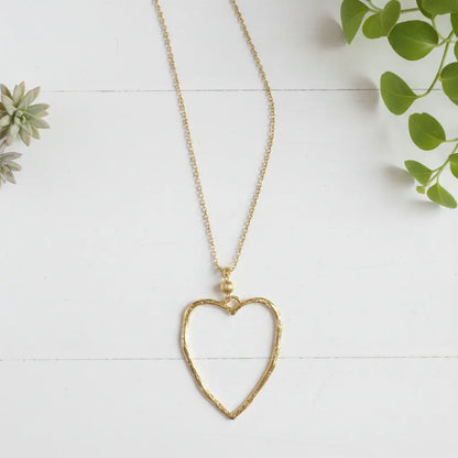 Gold plated chain necklace featuring an open heart pendant, styled as a fashionable jewelry accessory.