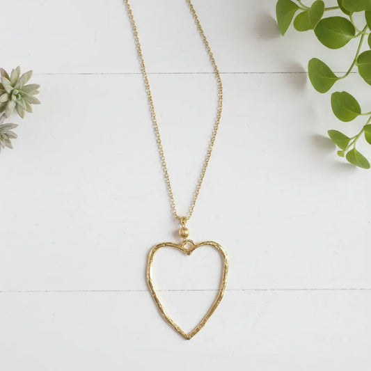 Gold plated chain necklace featuring an open heart pendant, styled as a fashionable jewelry accessory.