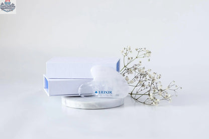 White crystal Gua Sha tool for facial massage and acupressure, made by LILIXIR, used for skincare and facial lifting.