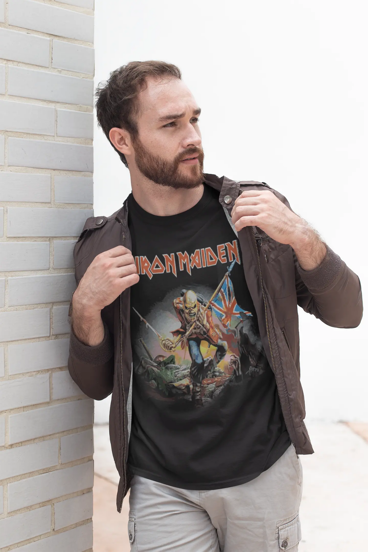 Black Iron Maiden The Trooper T-Shirt by Little Guitars featuring a bearded man leaning against a white brick wall.