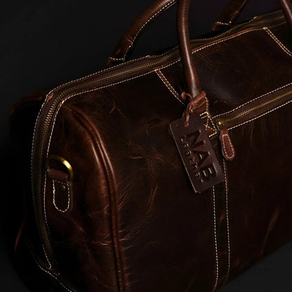 Brown leather duffle bag from NAB Leather's Wayfarer collection, featuring classic full-grain leather and sturdy handles.