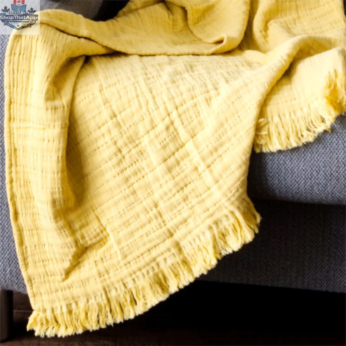 Close-up of Hem And Tassel wearable seersucker cotton throw in cozy ochre color, showcasing soft textured fabric and detailed stitching.