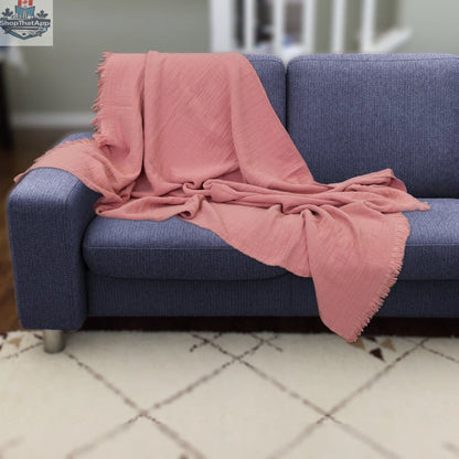 Pink wearable seersucker cotton throw by Hem And Tassel draped over a sofa, showcasing cozy, textured comfort in a stylish design.