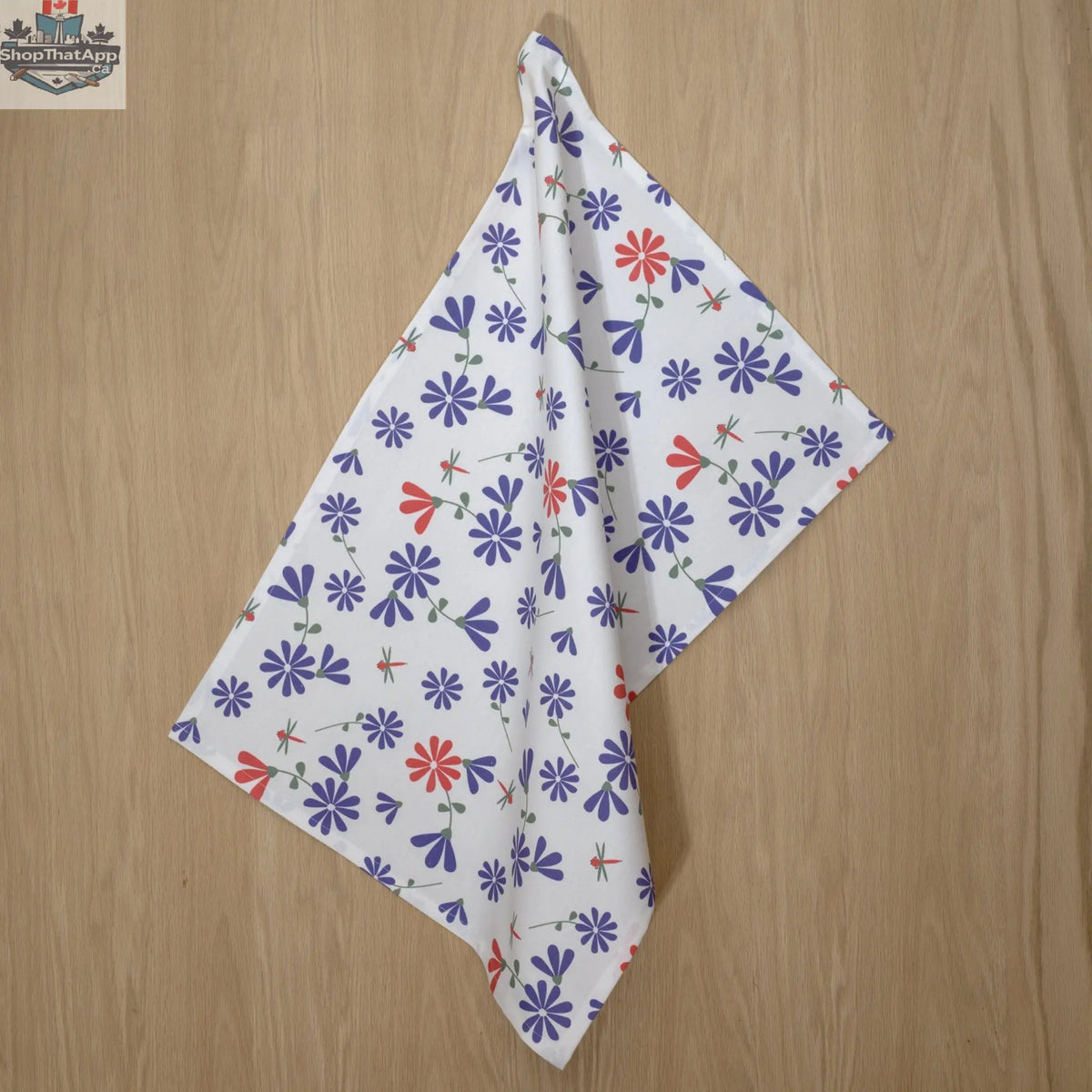Printed purple and pink Shy Dragonfly Tea Towel from Hem And Tassel hanging in a kitchen, showcasing vibrant dragonfly design.