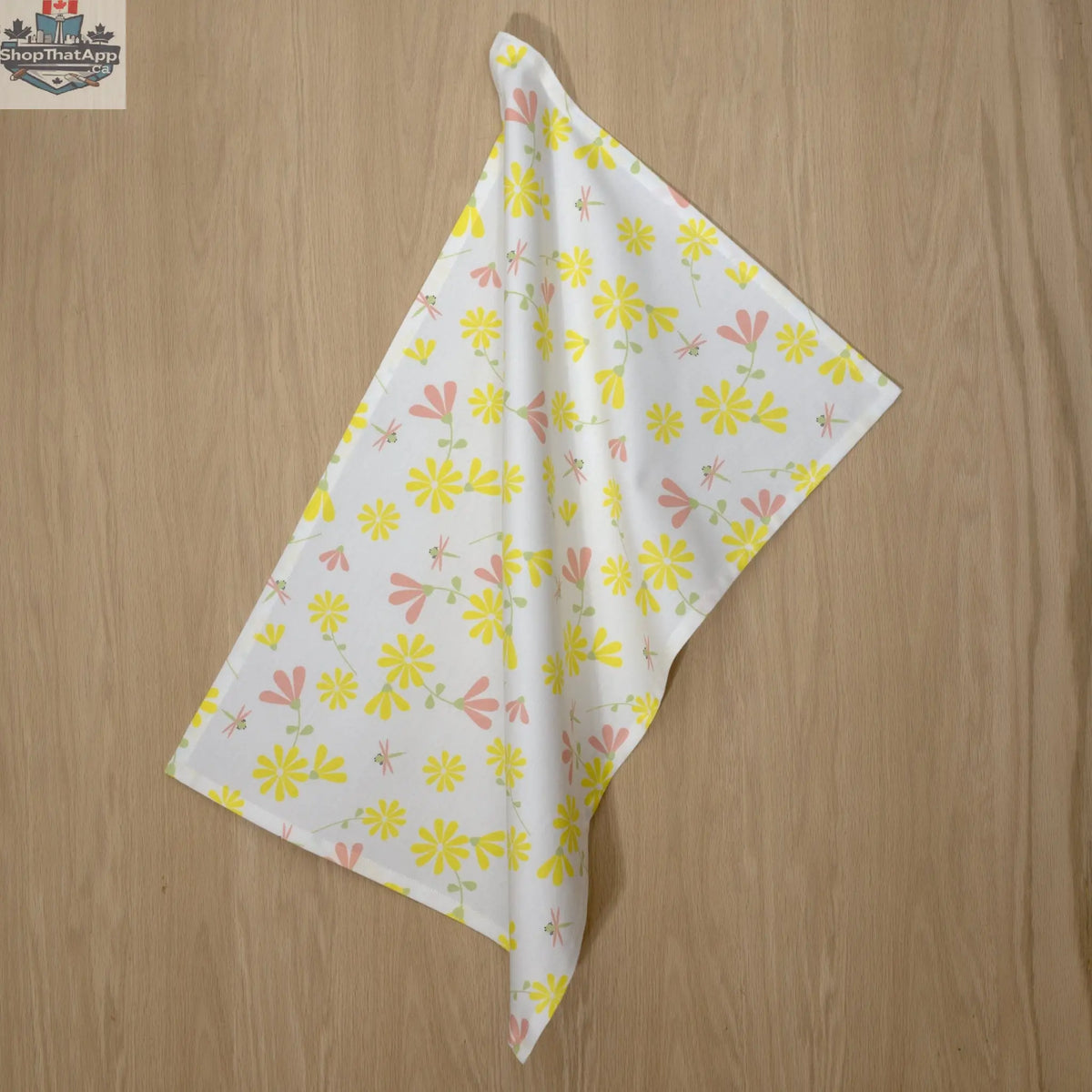 Yellow blush printed kitchen tea towel with a shy dragonfly design from Hem And Tassel, hanging on a kitchen hook.