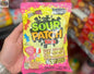Assorted Sour Patch Kids Lemonade candies in a 185g Snack Bar Co package, featuring bright yellow and colorful candy pieces.