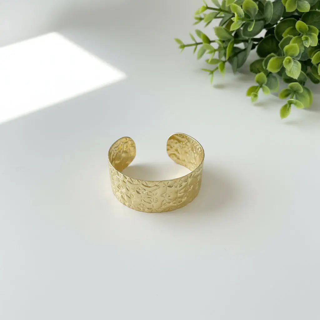 Gold stainless steel Beaten Cuff bracelet by Suzie Blue Canada, worn as a stylish accessory in a lifestyle setting.