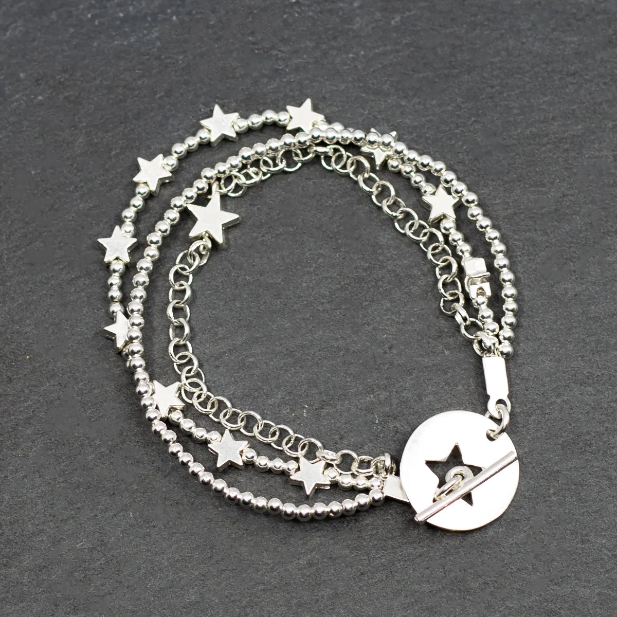 Silver star charm bracelet by Suzie Blue Canada featuring multi-strand design and T-bar clasp on a white background.