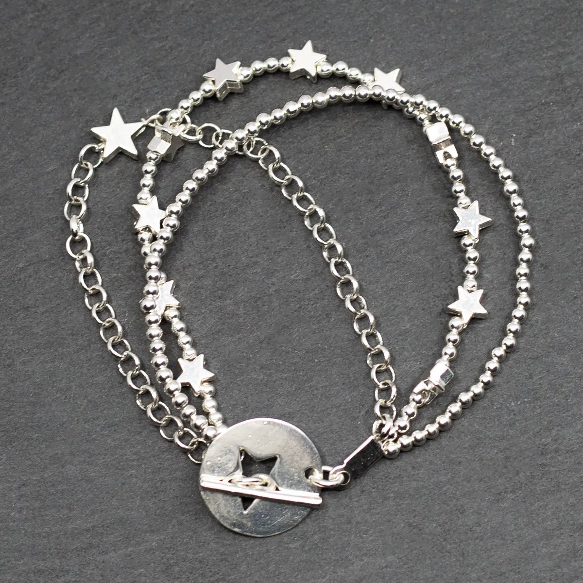 Silver star charm bracelet with multiple strands and T-bar clasp by Suzie Blue Canada, featuring a shiny metallic finish.