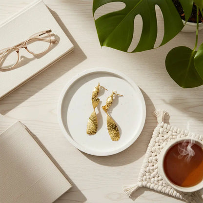 Gold stainless steel Beaten Metal Twist Earrings by Suzie Blue Canada displayed in a lifestyle setting.