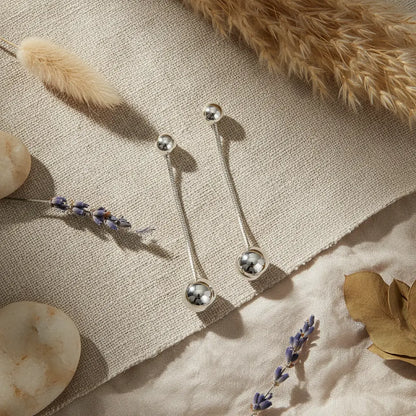 Grey stainless steel hanging ball stud earring by Suzie Blue Canada, featuring a sleek, minimalist design with a ball charm.